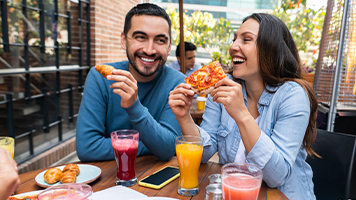 Comensales felices comiendo pizza en mesa de restaurante