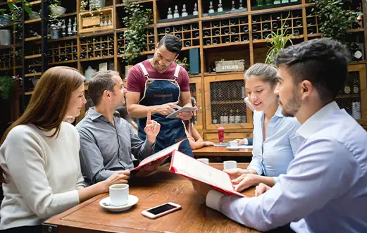 Comensale pidiendole a camarero en restaurante